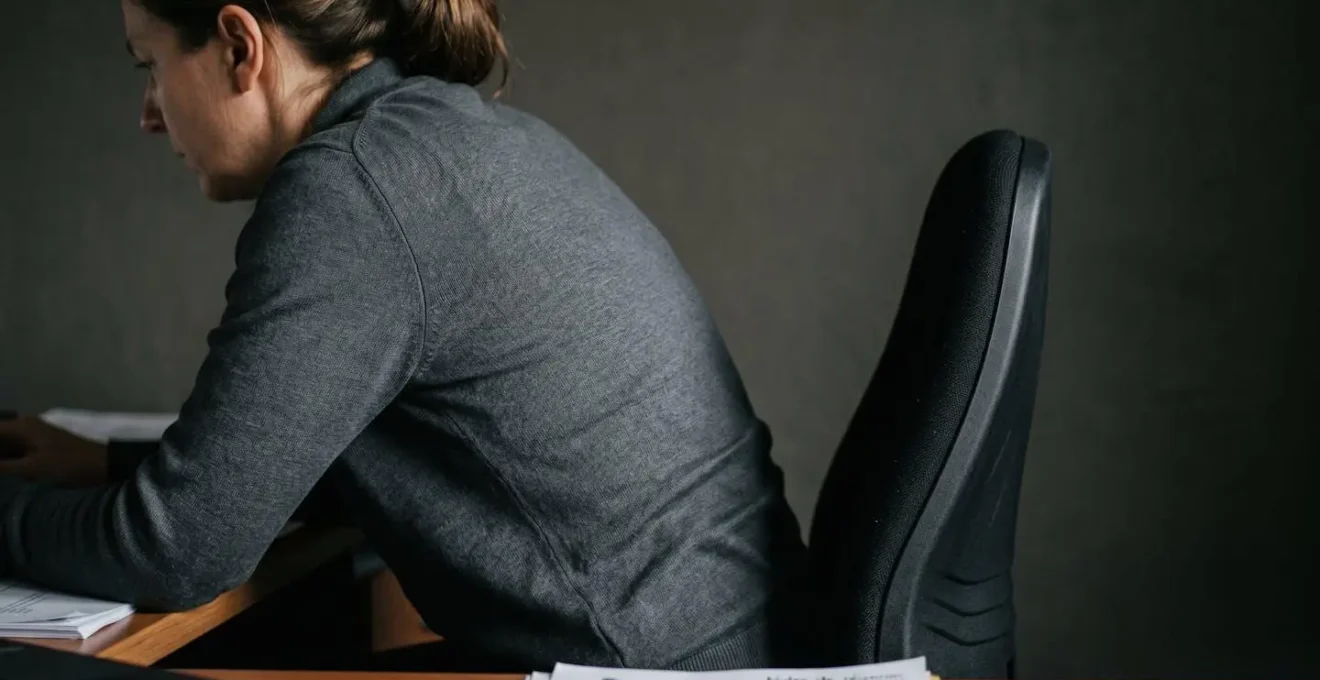 Vue latérale rapprochée montrant la posture assise et la courbure de la colonne vertébrale d'une personne sur un siège de bureau basique
